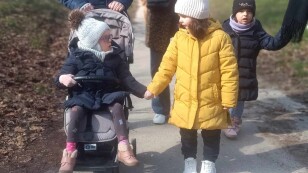 dwie dziewczynki (jedna na wózku inwalidzkim) spacerują, trzymając się za ręce