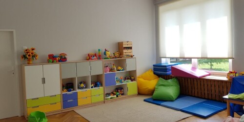 sala przedszkolna z kolorowymi regałami, materacami i poduchami sako