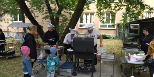 pracownicy przedszkola w czapkach kucharskich obsługują grill