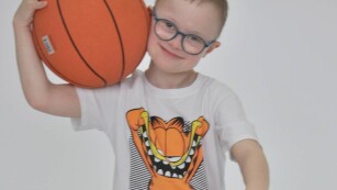 chłopiec z zespołem Downa trzyma dwie piłki do koszykówki